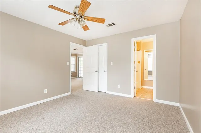 an empty room with closet and a ceiling fan