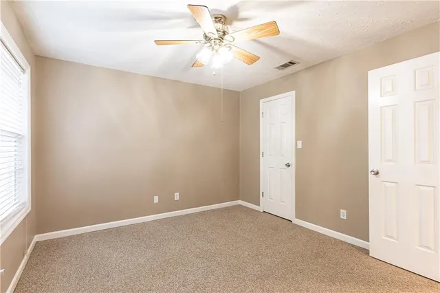 an empty room with windows and fan