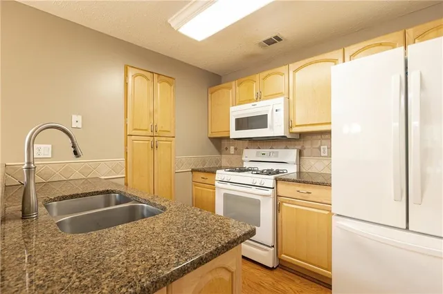 a kitchen with granite countertop a stove a sink and a refrigerator