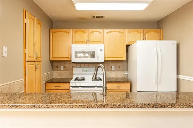 a kitchen with stainless steel appliances granite countertop a refrigerator a stove and a sink with large window