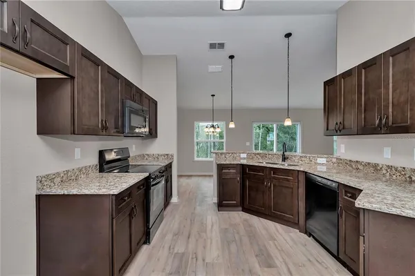 a kitchen with stainless steel appliances granite countertop sink stove top oven and microwave