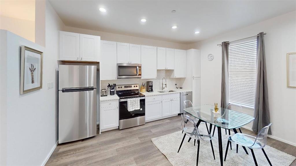 3235 Dallas Street, Unit 1201 Dallas, TX 75210 - Photo 14 of 26 a kitchen with a refrigerator a microwave oven a sink dishwasher and white cabinets with wooden floor