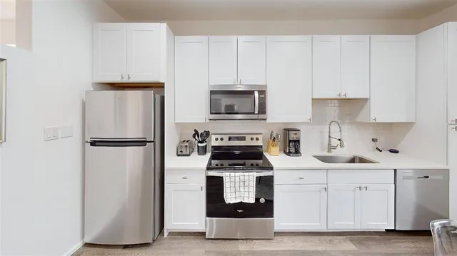 a kitchen with white cabinets and stainless steel appliances