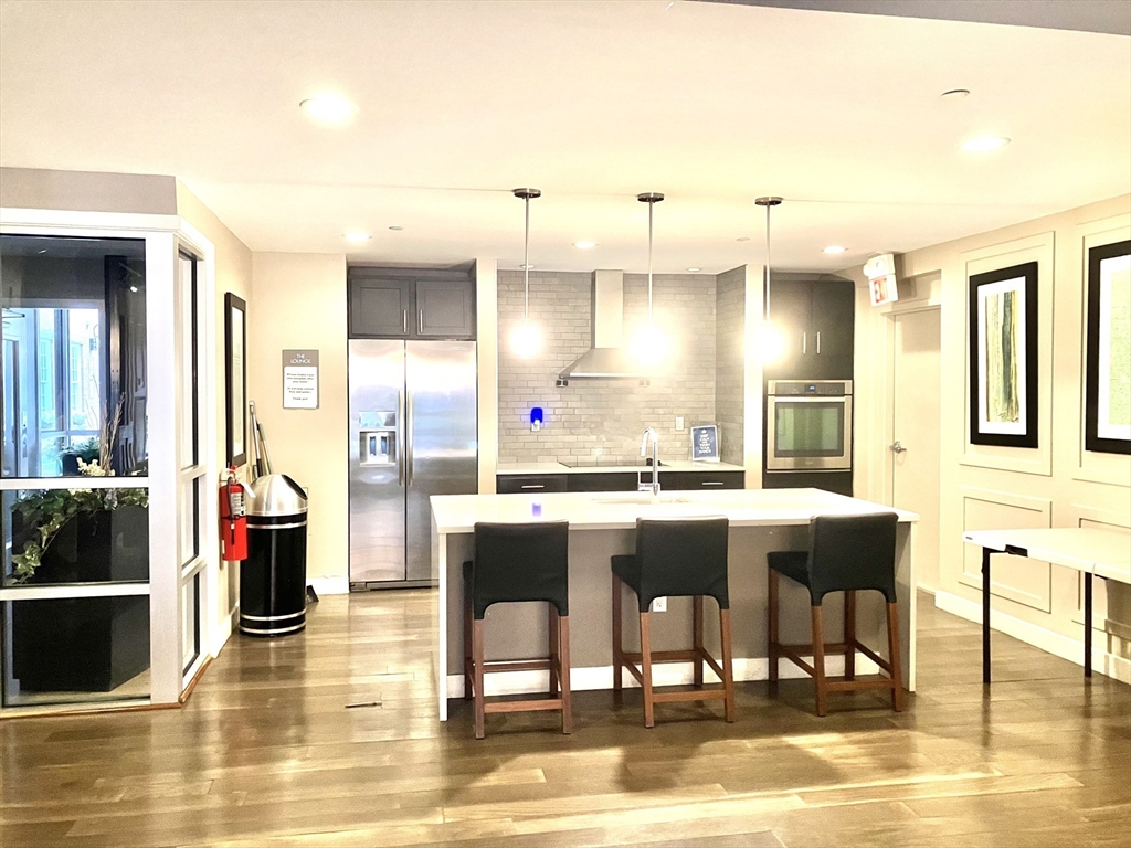 130 John Street, Unit G01 Lowell, MA 01852 - Photo 17 of 40 a dining hall with stainless steel appliances kitchen island granite countertop a table chairs in it and a wooden floor