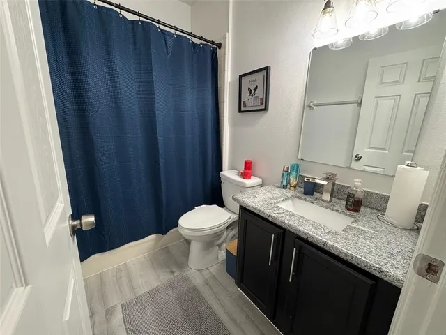 a bathroom with a granite countertop sink vanity mirror and toilet