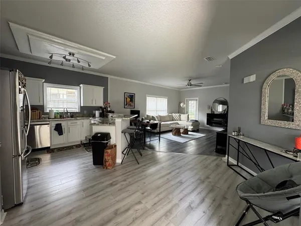 a view of living room kitchen with stainless steel appliances furniture stove and cabinets