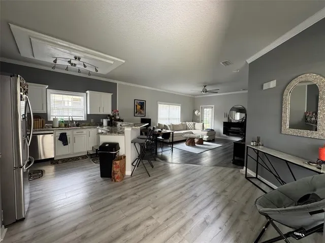 a view of living room kitchen with stainless steel appliances furniture stove and cabinets