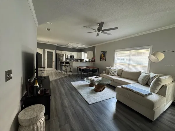 a living room with furniture kitchen view and a window