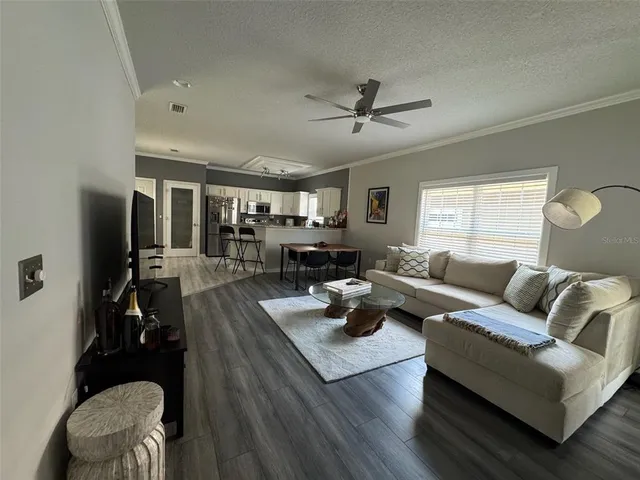 a living room with furniture kitchen view and a window