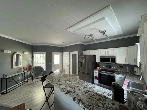 a kitchen with stainless steel appliances granite countertop a stove top oven a sink dishwasher a dining table and chairs with wooden floor