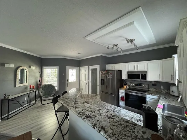 a kitchen with stainless steel appliances granite countertop a stove top oven a sink dishwasher a dining table and chairs with wooden floor