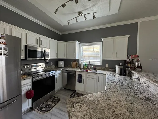 a kitchen with granite countertop a sink cabinets stainless steel appliances and a window