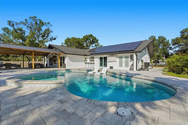 a view of a swimming pool with lawn chairs under an umbrella