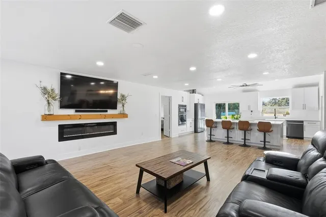 a kitchen with stainless steel appliances a refrigerator a stove top oven a sink dishwasher and white cabinets with wooden floor