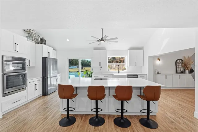a spacious bathroom with a double vanity sink a mirror a potted plant and a window