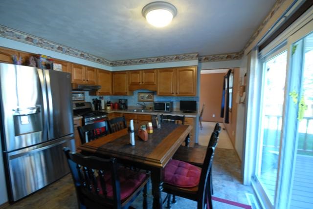 4154 Gloucester Road Roscoe, IL 61073 - Photo 6 of 22 a kitchen with stainless steel appliances granite countertop a refrigerator a stove a sink a dining table and chairs with the outer view