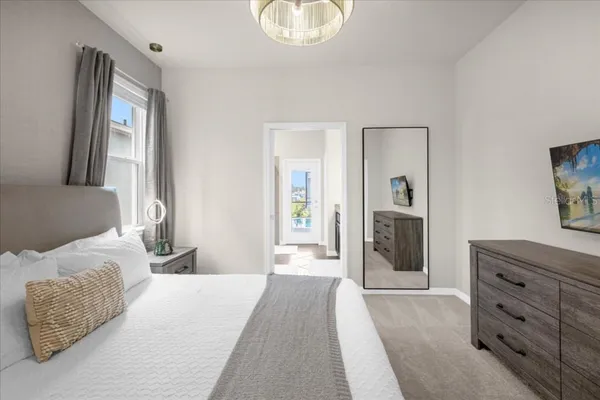 a bedroom with bed a chandelier and a window