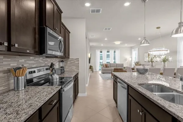 a kitchen with stainless steel appliances granite countertop a sink a stove and a wooden cabinets