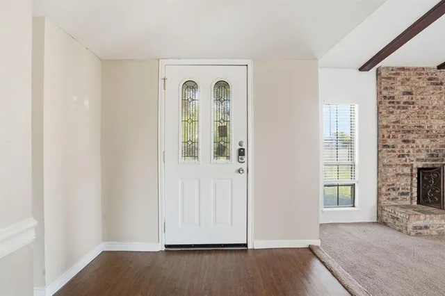 an empty room with wooden floor fireplace and windows