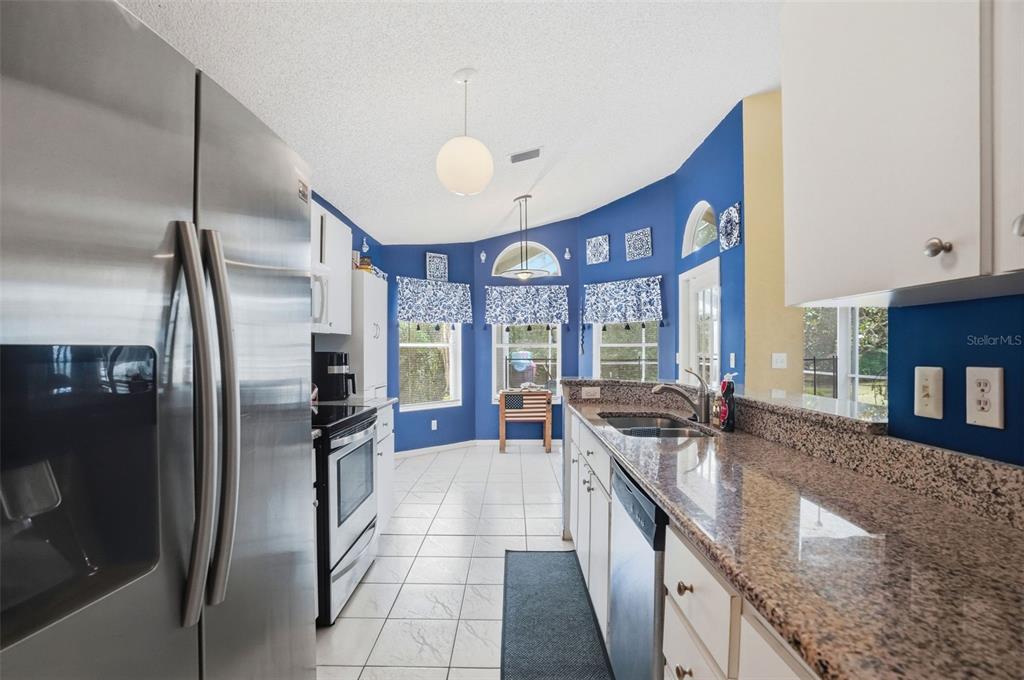 4219 Newton Road Spring Hill, FL 34606 - Photo 13 of 35 a kitchen with stainless steel appliances granite countertop a sink a stove and a refrigerator