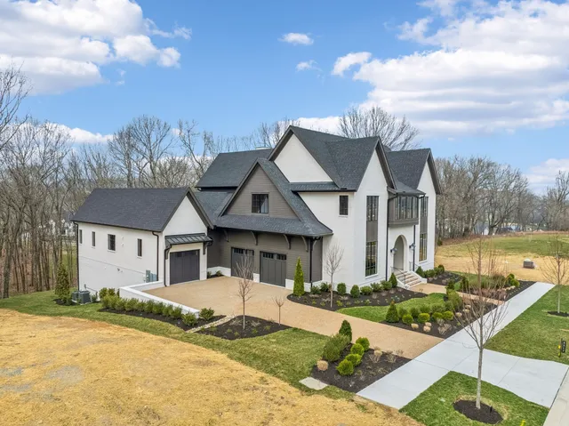 a view of a white house next to a yard with big trees