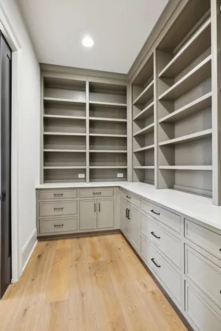 a view of an empty room with kitchen and wooden floor