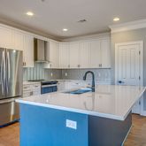 a kitchen with stainless steel appliances granite countertop a refrigerator a sink a stove and white cabinets with wooden floor