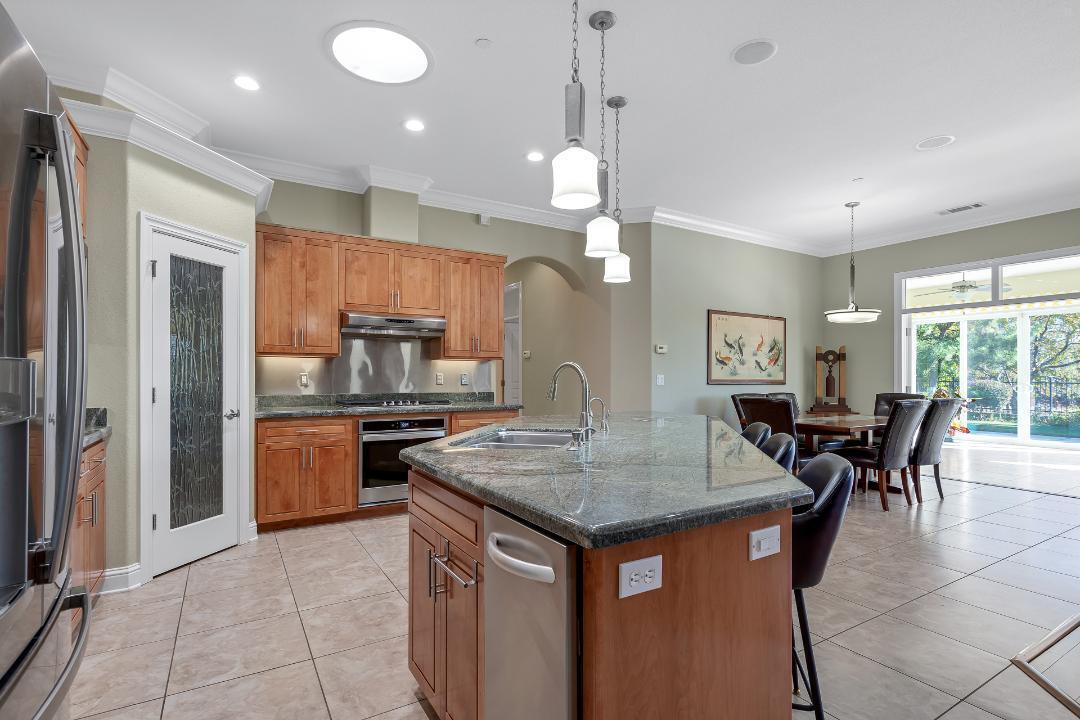 3685 Wimbledon Drive Redding, CA 96002 - Photo 20 of 70 a kitchen with kitchen island a dining table chairs and stainless steel appliances