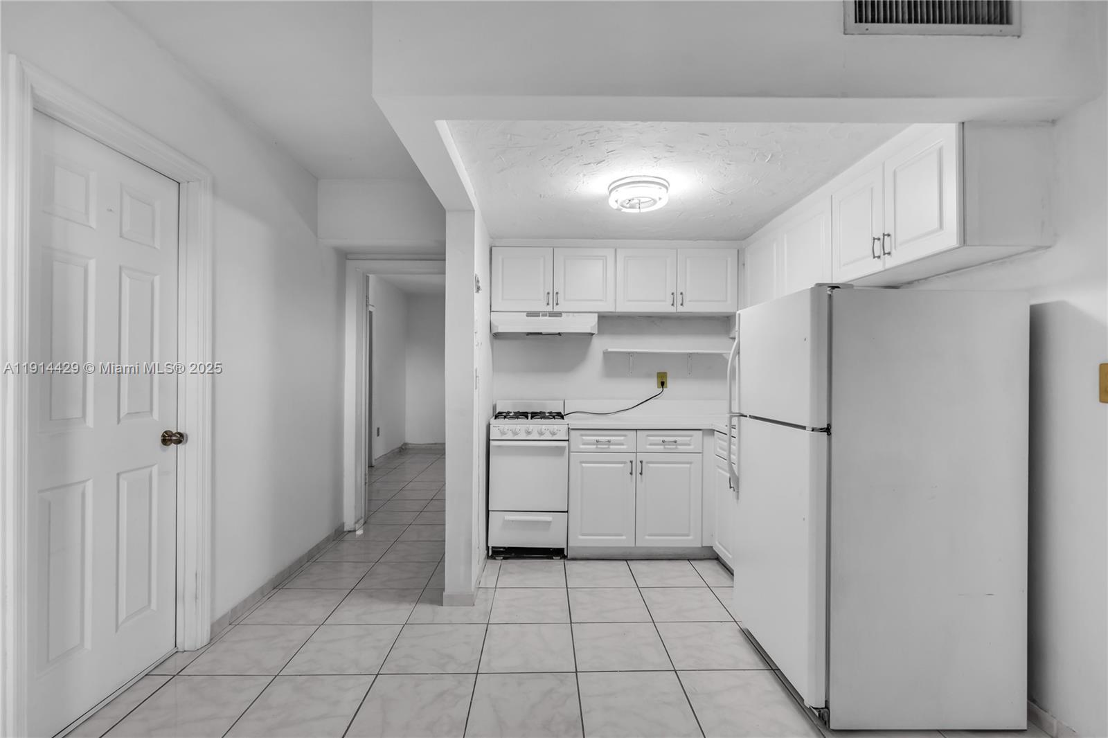 1330 West 54th Street, Unit 302C Hialeah, FL 33012 - Photo 6 of 20 a kitchen with white cabinets a refrigerator and a stove