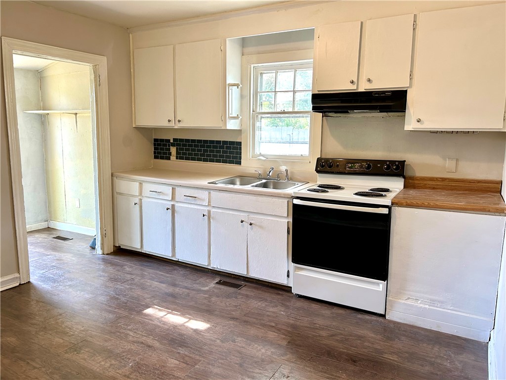 181 Sumter Street Anderson, SC 29621 - Photo 6 of 17 This kitchen offers functional cabinetry, a sink, and a range, creating a practical culinary space.