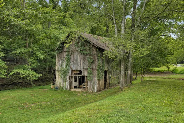 a view of a big house with a big yard and large trees