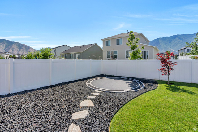 252 North Sunrise Rnch Drive Mapleton, UT 84664 - Photo 49 of 62 Spacious backyard featuring a full white vinyl privacy fence, manicured lawn, and a decorative rock landscape with stepping stones