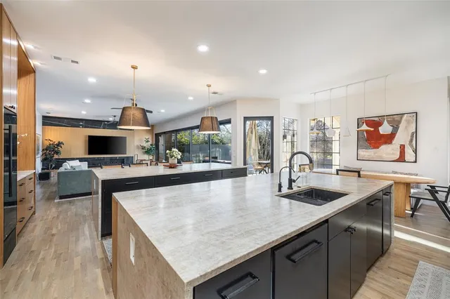 a kitchen with stainless steel appliances granite countertop a sink a stove and a wooden floors
