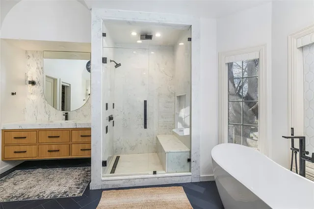 a bathroom with a tub shower sink and mirror