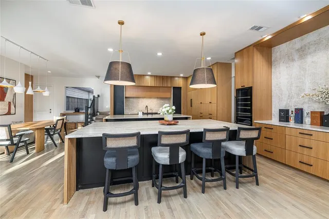 a kitchen with stainless steel appliances kitchen island granite countertop a table chairs sink and cabinets