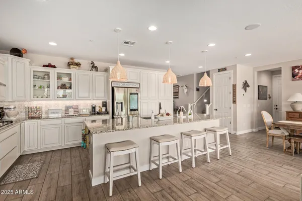 a kitchen with stainless steel appliances kitchen island granite countertop a kitchen island and chairs in it
