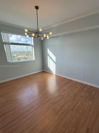 an empty room with wooden floor chandelier and windows