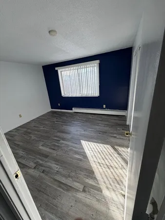 a view of an empty room with wooden floor and window
