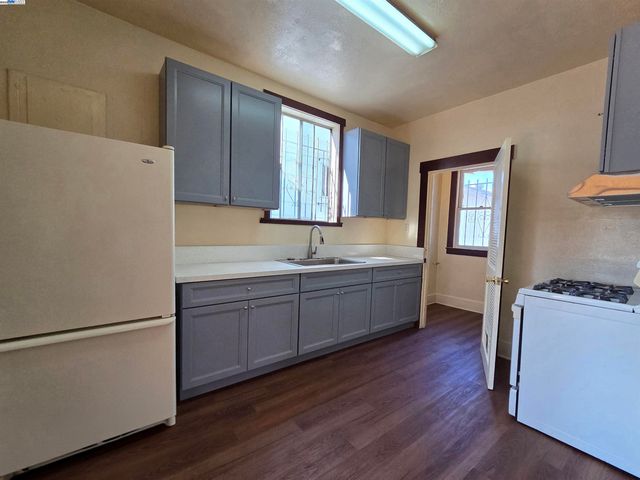 a kitchen with a refrigerator a sink and wooden floor