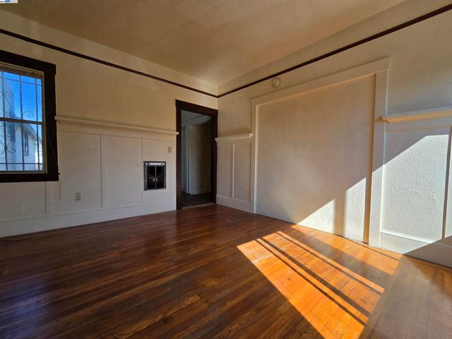 a view of an empty room with wooden floor and closet