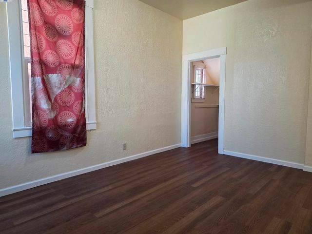 a view of an empty room with wooden floor and a painting