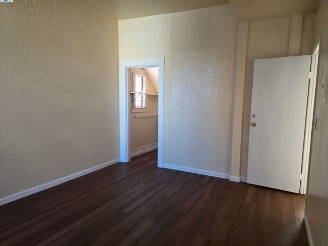 a view of an empty room with wooden floor and closet