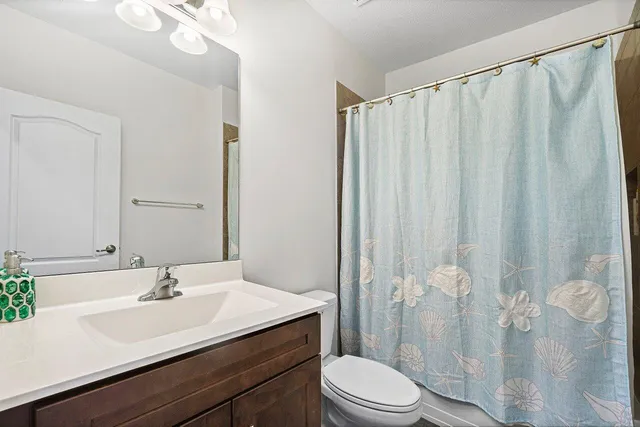 a bathroom with a sink a toilet and shower curtain