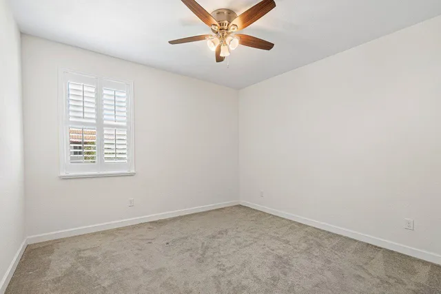 an empty room with a window and a fan