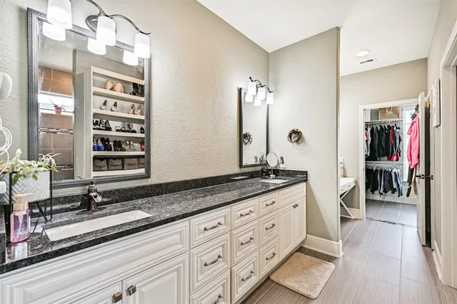 a bathroom with a granite countertop sink a large mirror and a toilet