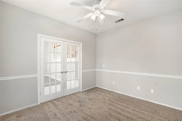 an empty room with windows and chandelier fan