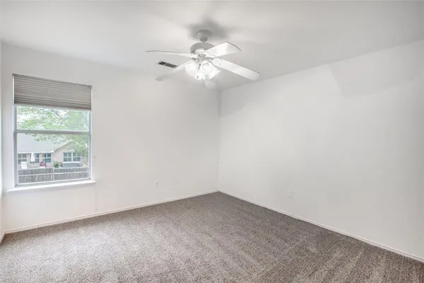 an empty room with a window and a fan