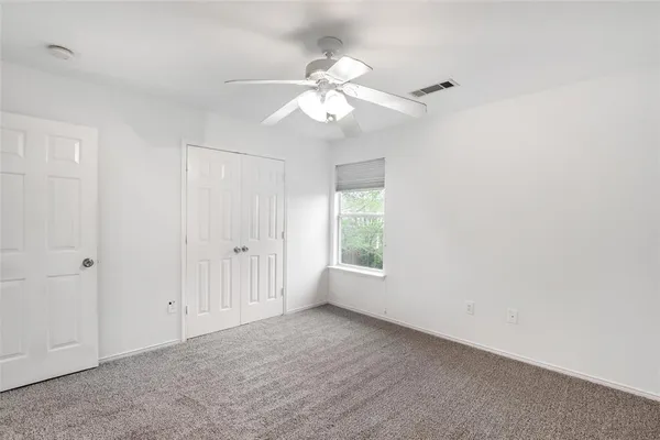 an empty room with a ceiling fan and a window