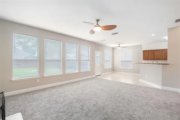 an empty room with chandelier fan and windows