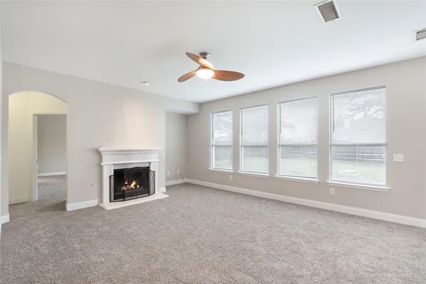 a view of an empty room with wooden floor fireplace and a window